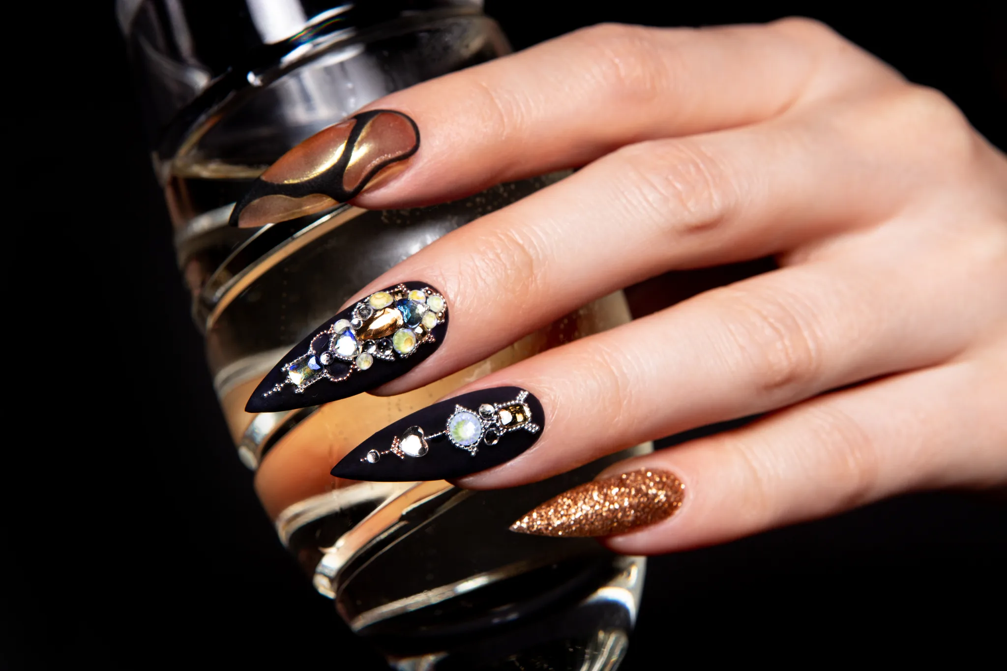 gold nail art beside a champagne glass against black