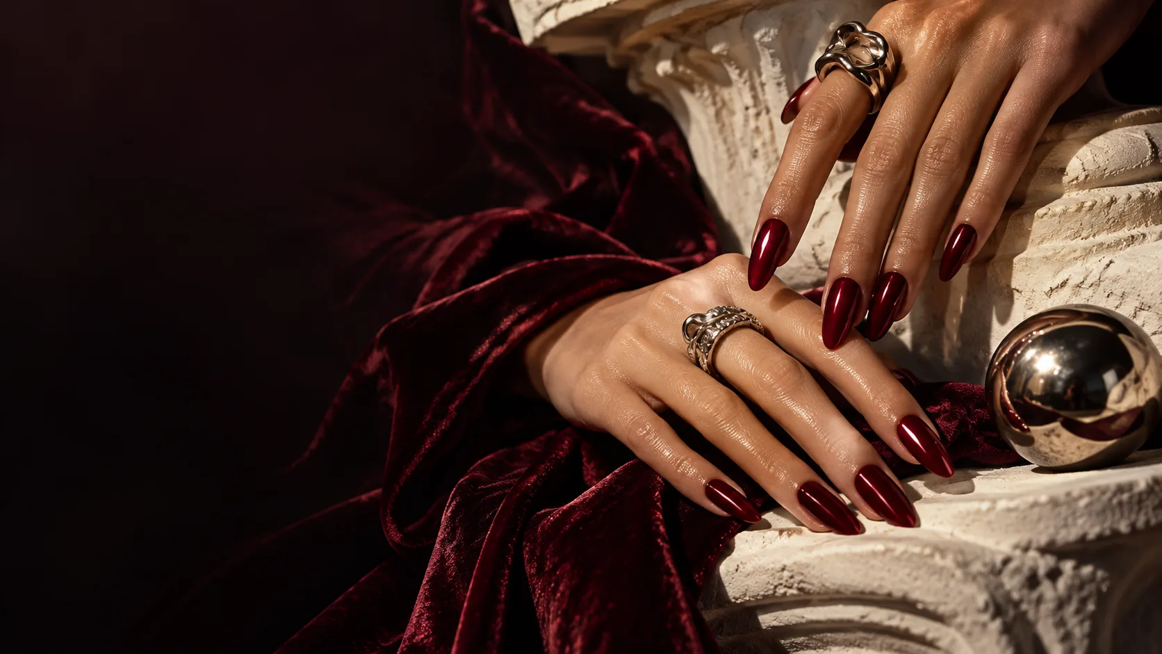 burgundy manicured hands on crimson velvet and a marble column